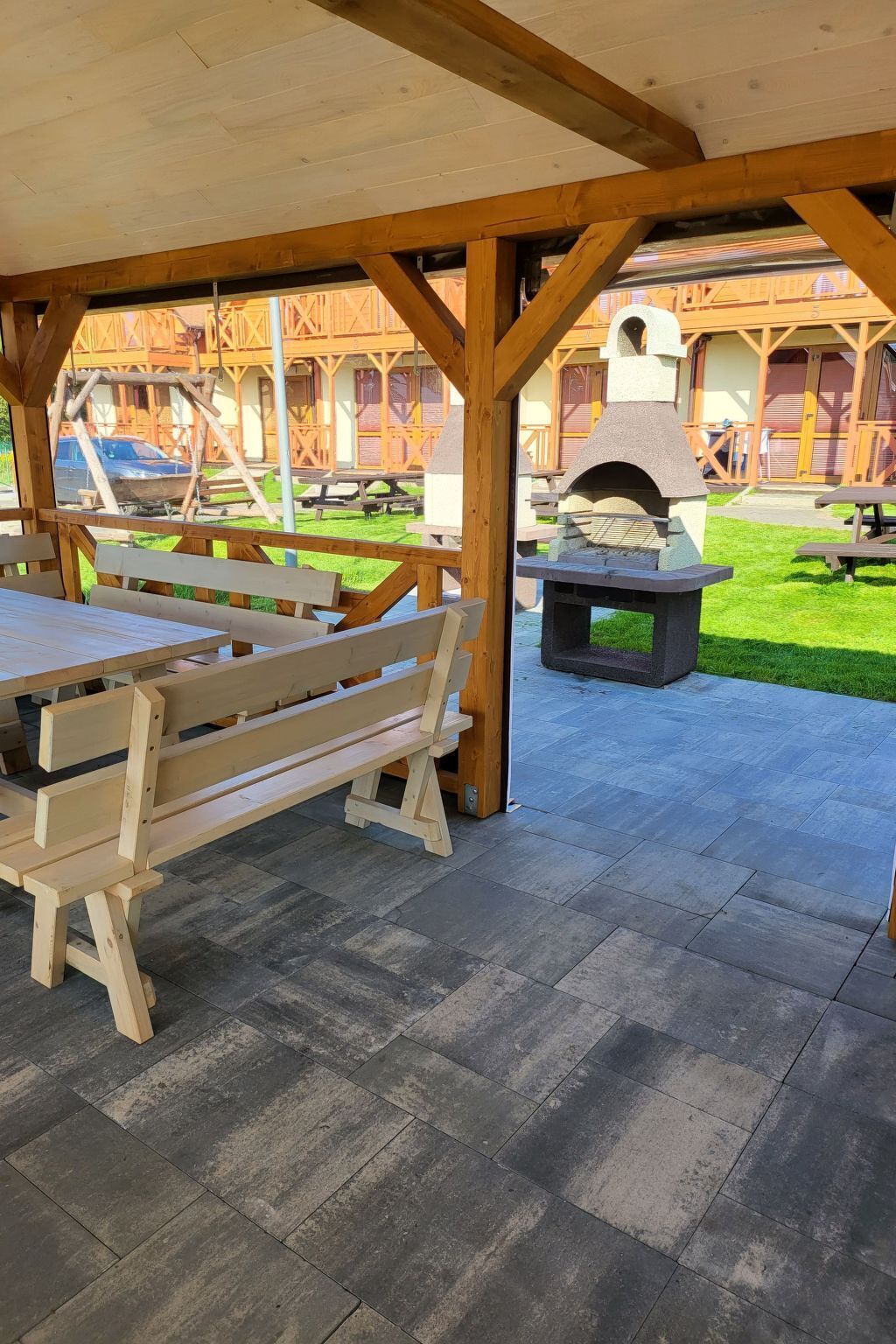 An outdoor patio with wooden benches and a stone barbecue grill.