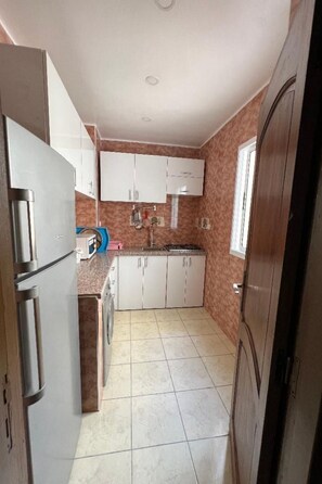 A compact kitchen with white cabinets, a stainless steel refrigerator, a gas stove, and a washing machine. - Geräumige Ferienwohnung für 12 Personen by Interhome (Agadir)