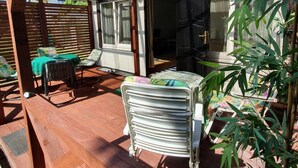 Een overdekt terras met houten banken en een tafel, omringd door bamboeplanten.