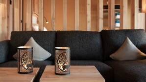 Uma sala de estar moderna com um sofá cinza escuro, dois castiçais decorativos e uma mesa de centro de madeira.