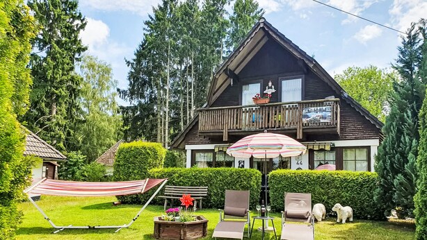 Una casa di legno con un balcone, un'amaca e mobili da esterno.