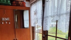 Una porta in legno con un cartello 'HOME', una finestra con tende di pizzo e vista su un paesaggio verde.