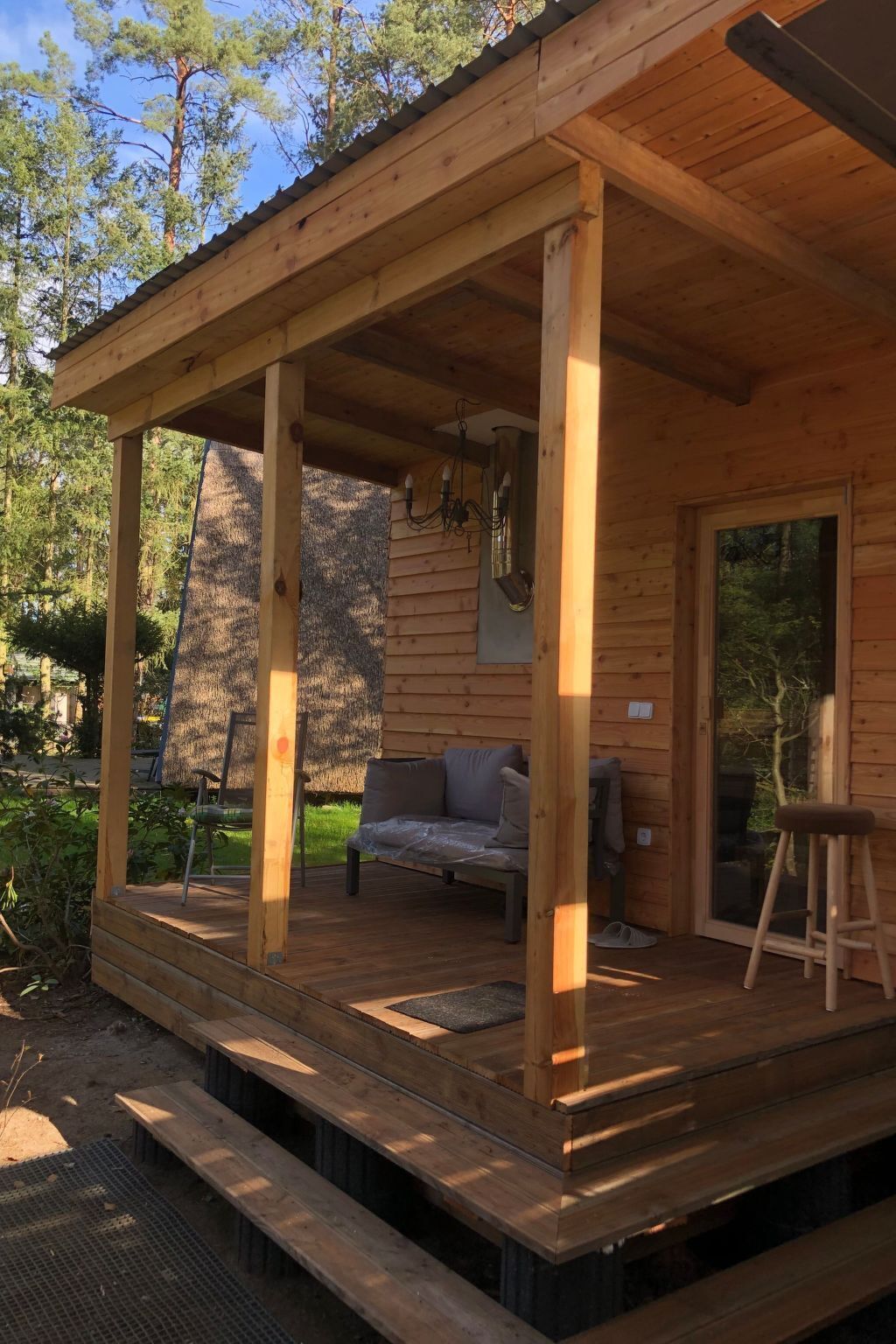 A wooden cabin with a covered porch, a sofa, and a ladder.