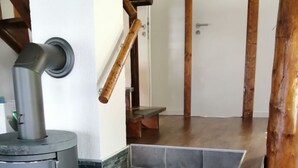 Ein modernes Interieur mit Kaminofen, einer Treppe mit dunklen Fliesen und Holzbalken.