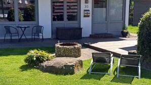 Ein zweistöckiges Haus mit Balkon, Hausnummer 30 und einer Terrasse mit Sitzgelegenheiten.