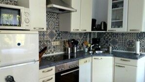 Cocina con armarios blancos, microondas, horno y lavaplatos.