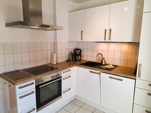 Een koelkast, een oven, een vaatwasser, kookgerei, borden en bestek