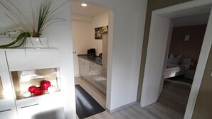 A modern kitchen with white cabinets, a coffee machine, and a dining area with a table and chairs. - Urlaub und zu Hause by Interhome (Naundorf)
