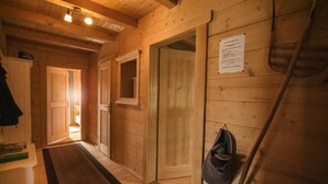 Interior de madera con suelo de madera, un banco, una puerta y un bolso colgado en la pared.