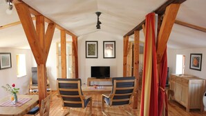 A cozy room with wooden beams, a dining table with chairs, a TV, and a cabinet. - "Galerie" by Interhome (Kröslin)