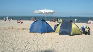 A beach with tents and an umbrella. - "Galerie" by Interhome (Kröslin)