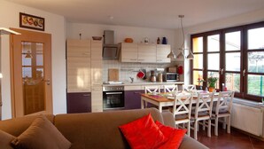 A modern kitchen with white cabinets, a dining area with white chairs, and a brown sofa with red cushions. - Abendsonne by Interhome (Mirow)