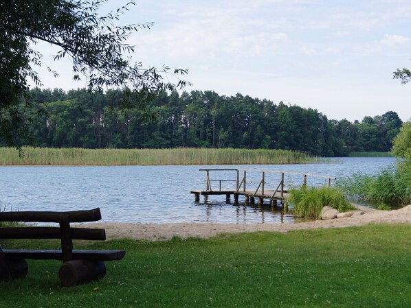 A lakeside park with a wooden dock and a picnic table.