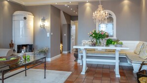 A spacious living room with a fireplace, a dining area with a white table and bench, and a chandelier. - Sönshörn - S20 - in Munkmarsch by Interhome (Archsum)
