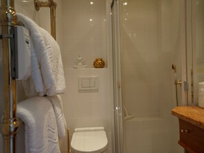 Ein Badezimmer mit einer Duschkabine, einer weißen Toilette und einem Waschtisch mit Marmorplatte.