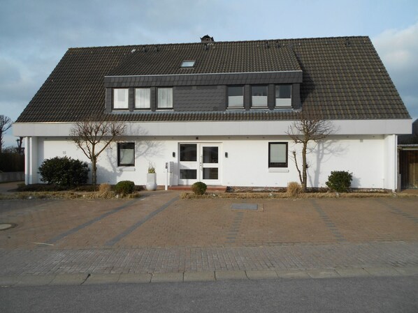 Ein zweigeschossiges Haus mit einem Ziegeldach, einer Haustür und einer Garage.