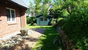 Une maison en briques avec un chemin pavé menant à un abri de jardin.
