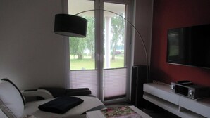 Habitación de hotel con cama, escritorio con computadora, televisión y ventana con persianas.