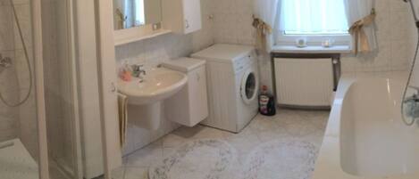A bathroom with a sink, washing machine, and bathtub.