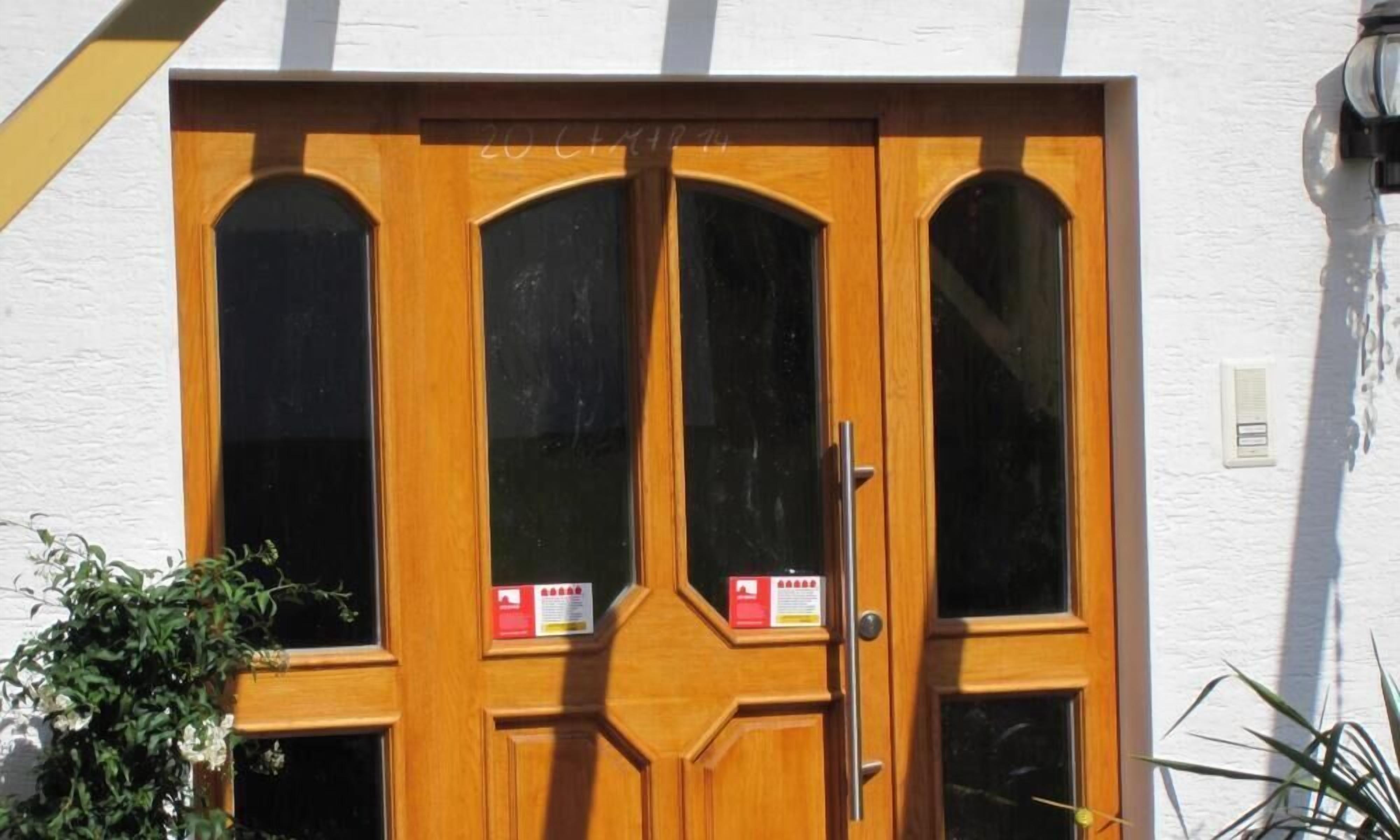 Une porte en bois avec trois panneaux de verre et une poignée en métal.
