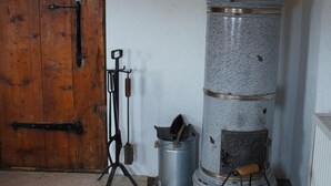 Una habitación rústica con un gran puerta de madera, un horno de piedra y un balde de metal.