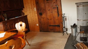 Una habitación rústica con muebles de madera, un gran portón de madera y una estufa de metal.