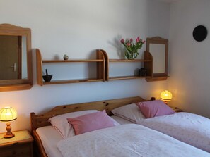 Une chambre avec deux lits, des têtes de lit en bois, des lampes de chevet, un miroir et des étagères ornées d’objets décoratifs.