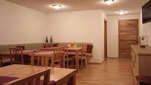 Een zithoek met houten meubels, een bank en een aan de muur bevestigde televisie.