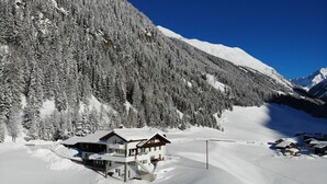 Een bergresort bedekt met sneeuw, met een chalet en dichte bossen en besneeuwde hellingen.