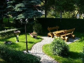 Un giardino con un vialetto lastricato, una panchina in legno e un lampione.