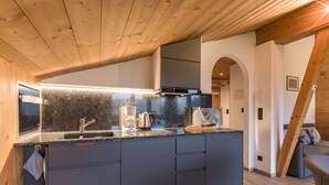 Una cucina moderna con un piano di lavoro in granito, mobili scuri e forno incassato.