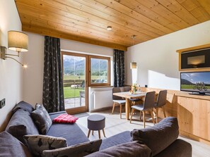 Ein gemütliches Wohnzimmer mit einer Couch, einem Esstisch mit Stühlen und einem Fernseher.