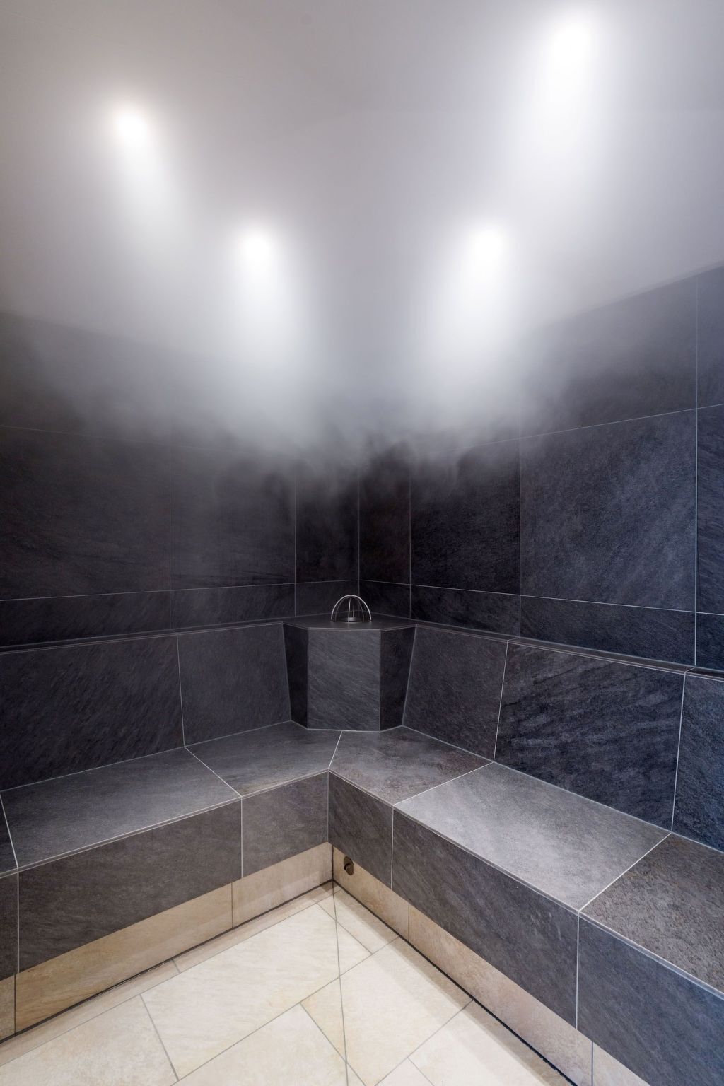 Un baño de vapor con paredes de piedra oscura y bancos.