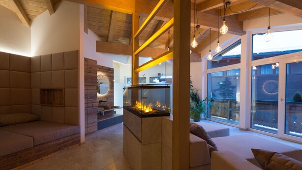 Ein modernes Wohnzimmer mit Kamin, gemütlicher Sitzgelegenheit und großen Fenstern.