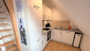 A compact kitchen with white cabinets, a built-in oven, and a coffee maker. - Martina by Interhome (Friederikensiel)