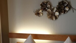 A hotel room with a wooden headboard, white bedding with floral patterns, and decorative wall art. - Ruhiges Landhaus mit zwei gemütlichen Wohnungen by Interhome (Bereborn)