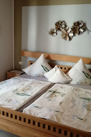 Una cama doble con ropa de cama floral, cabecera de madera y decoración en la pared.