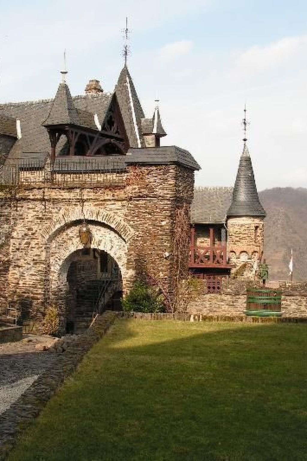 Ein historisches Steinhaus mit markantem Rundbogenportal, einem Turm mit einer spitzen Kuppel und einem kleinen Garten davor.