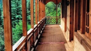 Un pasillo cubierto de madera con suelo en patrón de espiga, barandillas de madera y vistas a un bosque frondoso.