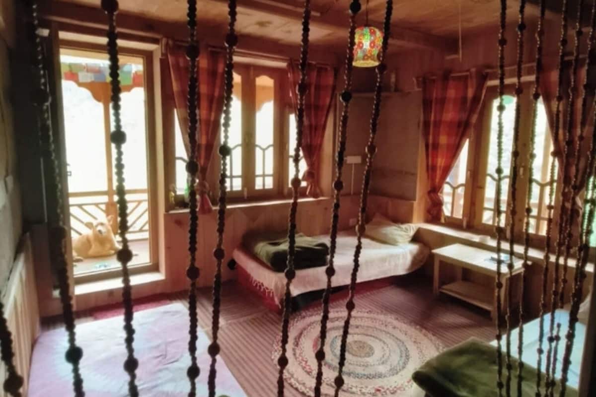 A cozy room with a bed, a small table, and a window with curtains.