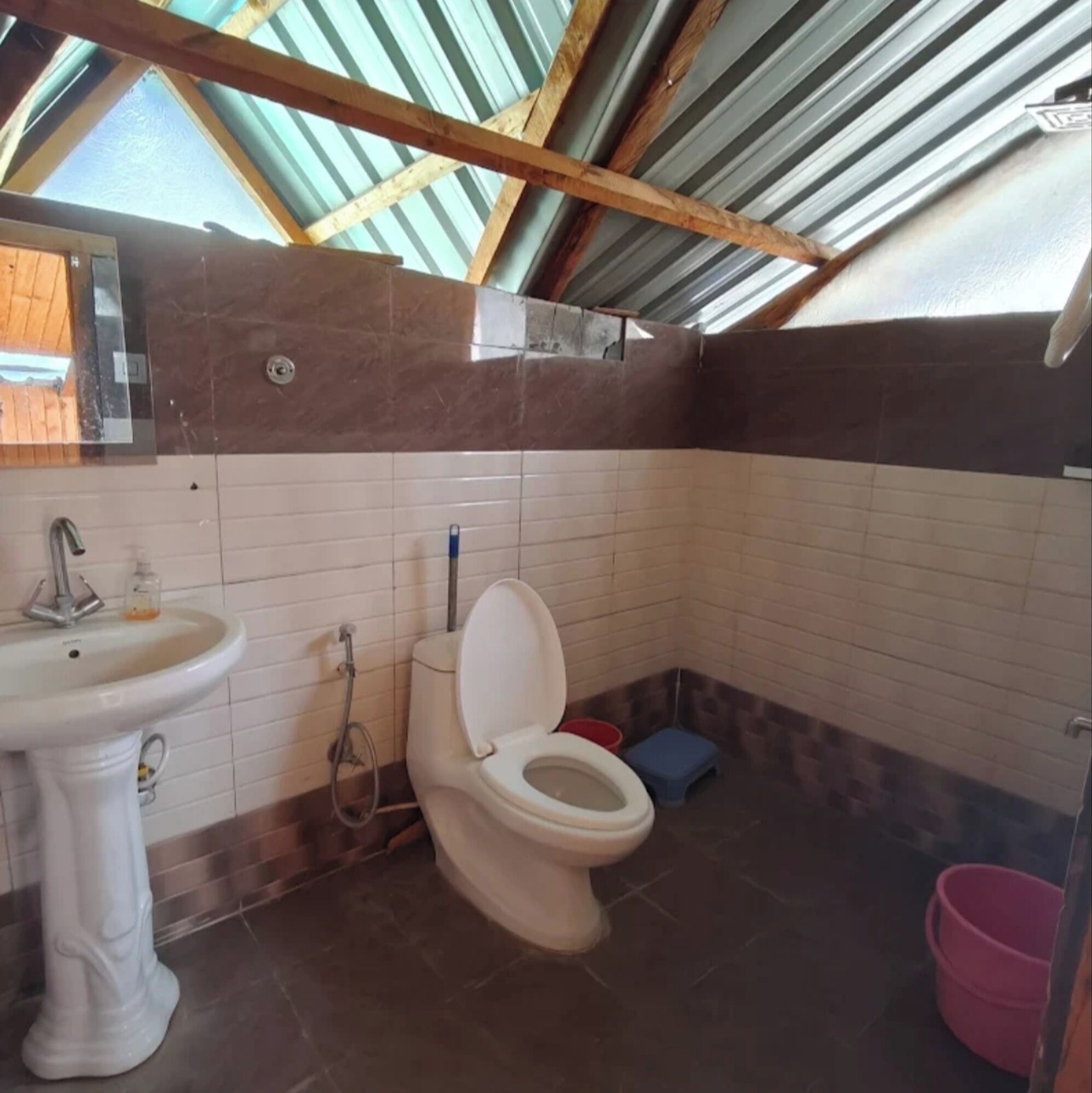 Casa de banho compacta com sanita, lavatório e chuveiro.