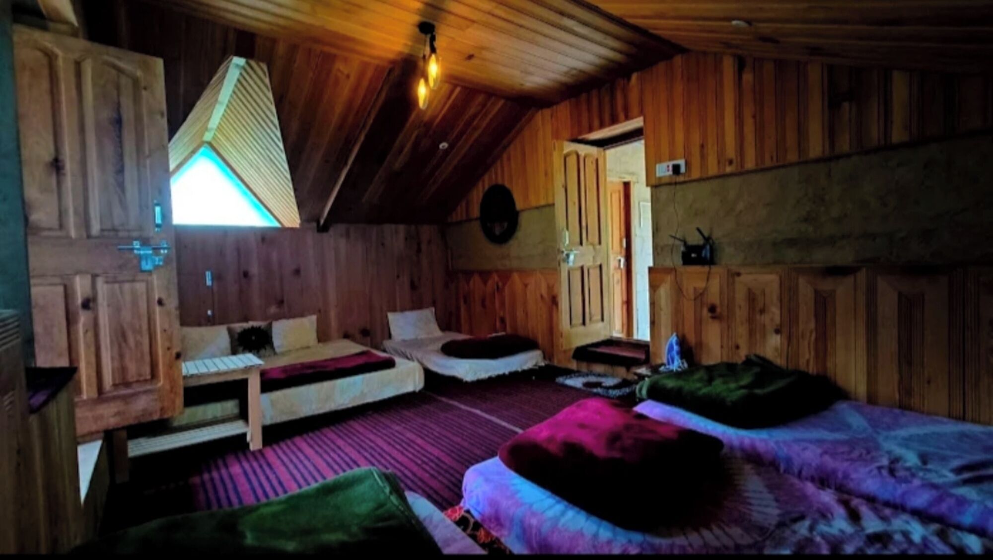 A cozy cabin with two beds, a wooden ceiling, and a small window.