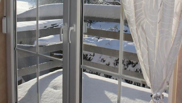 A room with a large sliding glass door leading to a balcony with a snowy landscape view. - Wohnung in Heringhausen mit Grill by Interhome (Diemelsee)