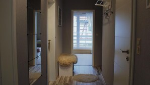 A narrow hallway with a wooden floor, a small stool, and a window with blinds. - Wohnung in Heringhausen mit Grill by Interhome (Diemelsee)