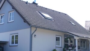 A two-story building with a tiled roof, a balcony, and a small porch with potted plants. - Wohnung in Heringhausen mit Grill by Interhome (Diemelsee)