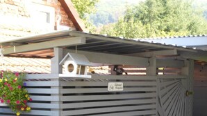 A metal shed with horizontal slats, a small attached structure, and a flower box. - Wohnung in Heringhausen mit Grill by Interhome (Diemelsee)