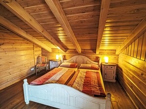 Ett sovrum i en stuga med träpanel, en vit säng, två sängbord och en sänggavel.