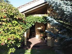 A house with a covered porch, a potted plant, and a tree with red berries. - Gemütliches Blockhaus in Waldrandlage mit Sauna by Interhome (Drübeck)