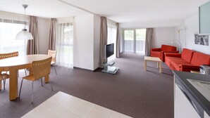 Een moderne woonkamer met een eethoek, een rode bank en een televisie.