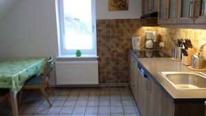 Een kleine keuken met een raam, een radiator, een koffiezetapparaat en een spoelbak.